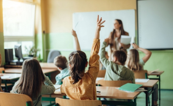 Students raising hands while teacher asking them questions in classroom